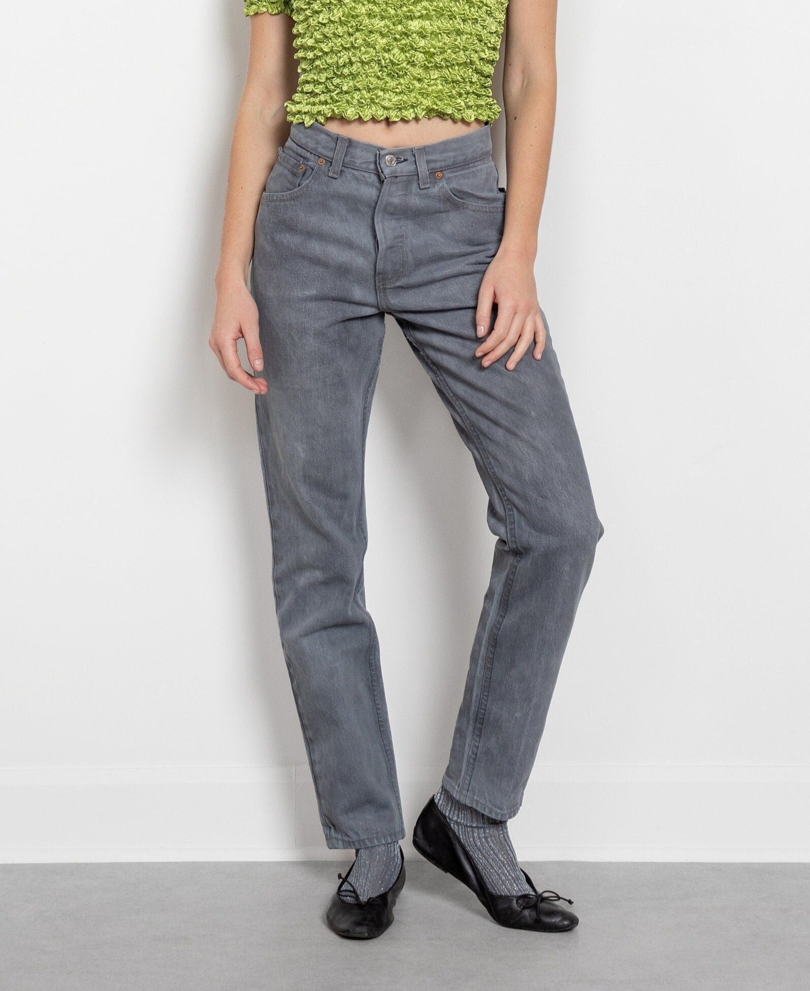 A pair of vintage gray Levi's 501 button fly jeans, displayed on a model without showing the upper part of the body.