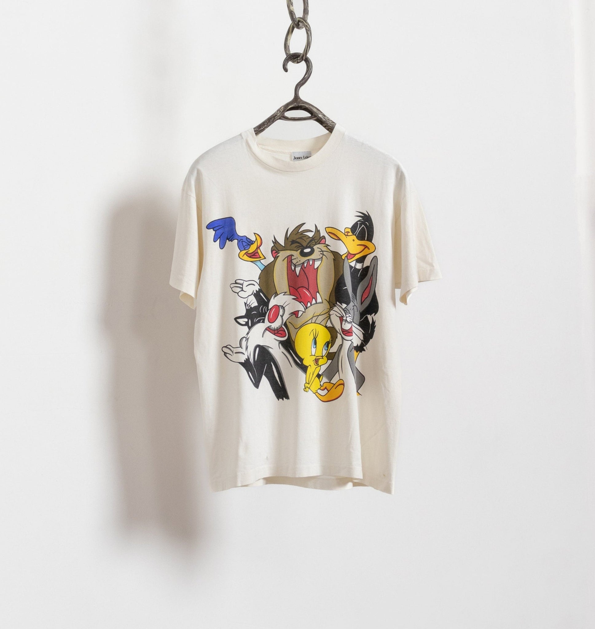 Beige t-shirt with cartoon character design on a hanger against a white background