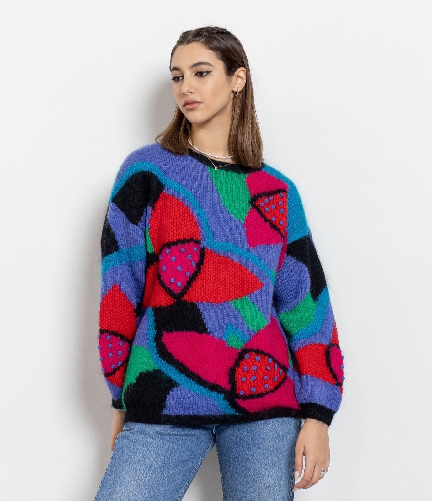 Woman wearing a colorful abstract-patterned sweater against a white background