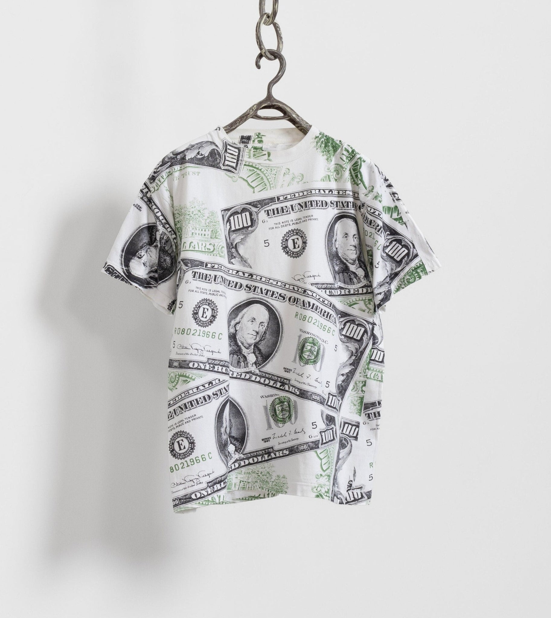 T-shirt with dollar bill design hanging on a white background