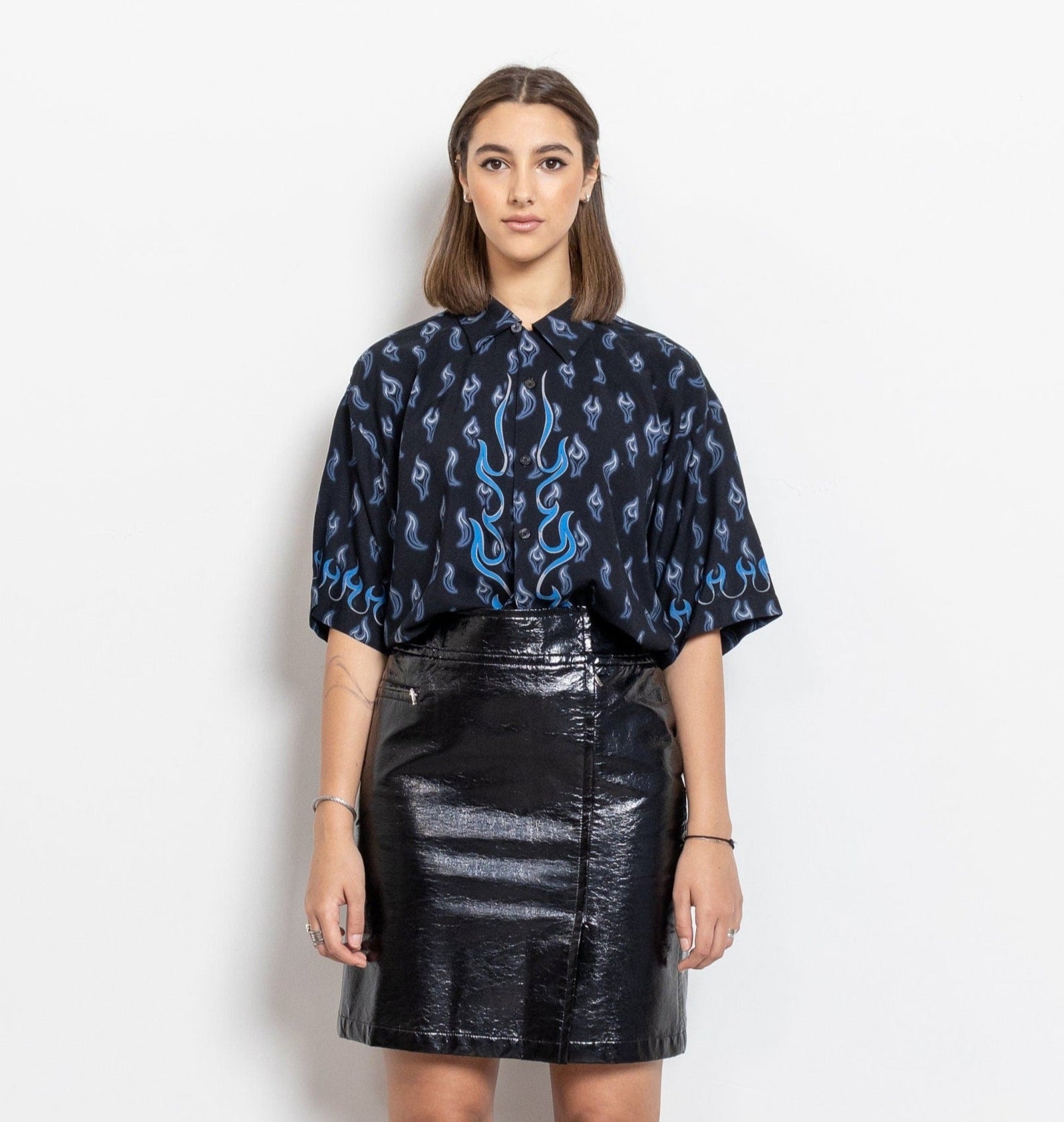 Woman wearing a black and blue patterned blouse with a black leather skirt on a white background
