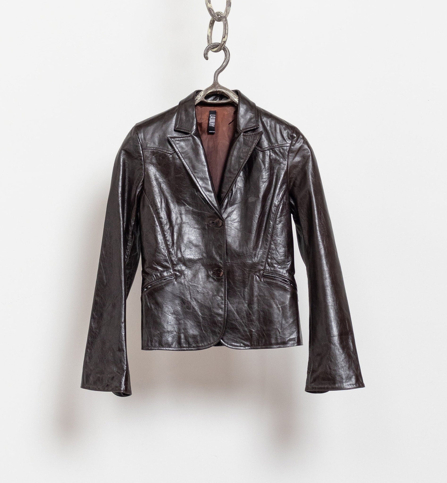 Black leather jacket hanging on a silver chain against a white background