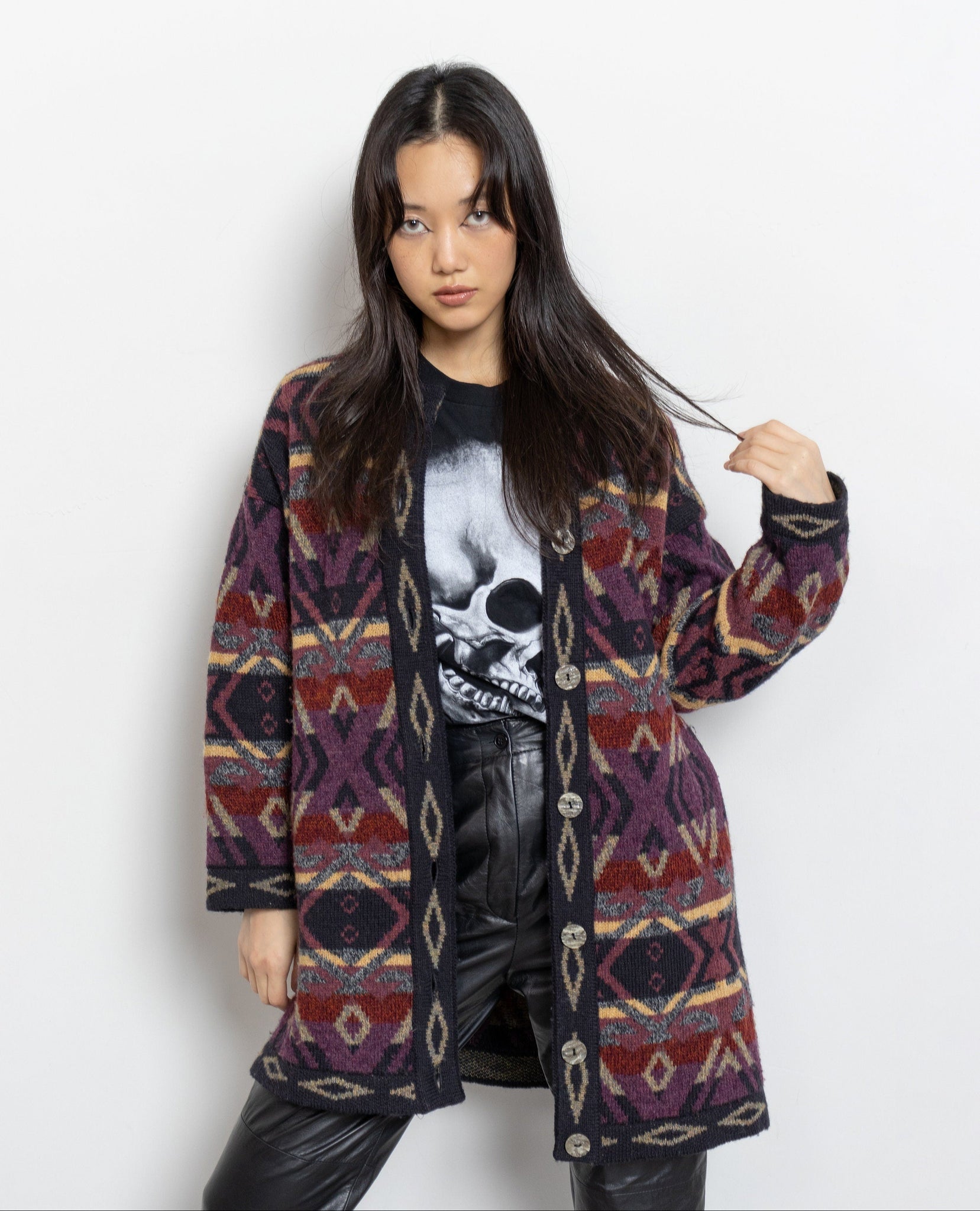 Woman wearing a patterned coat over a black shirt with a skull design on a white background