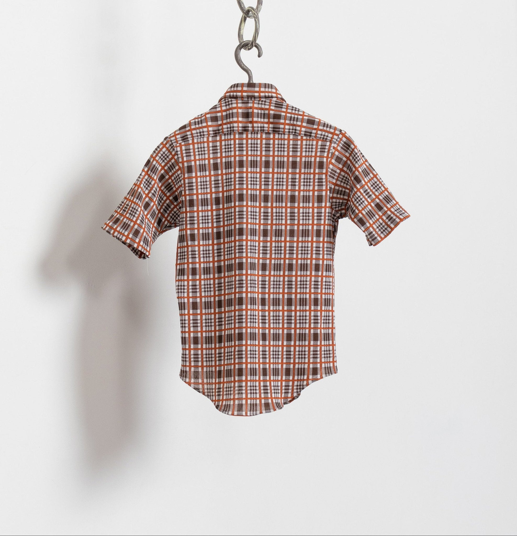 Plaid shirt hanging on a hook against a white background