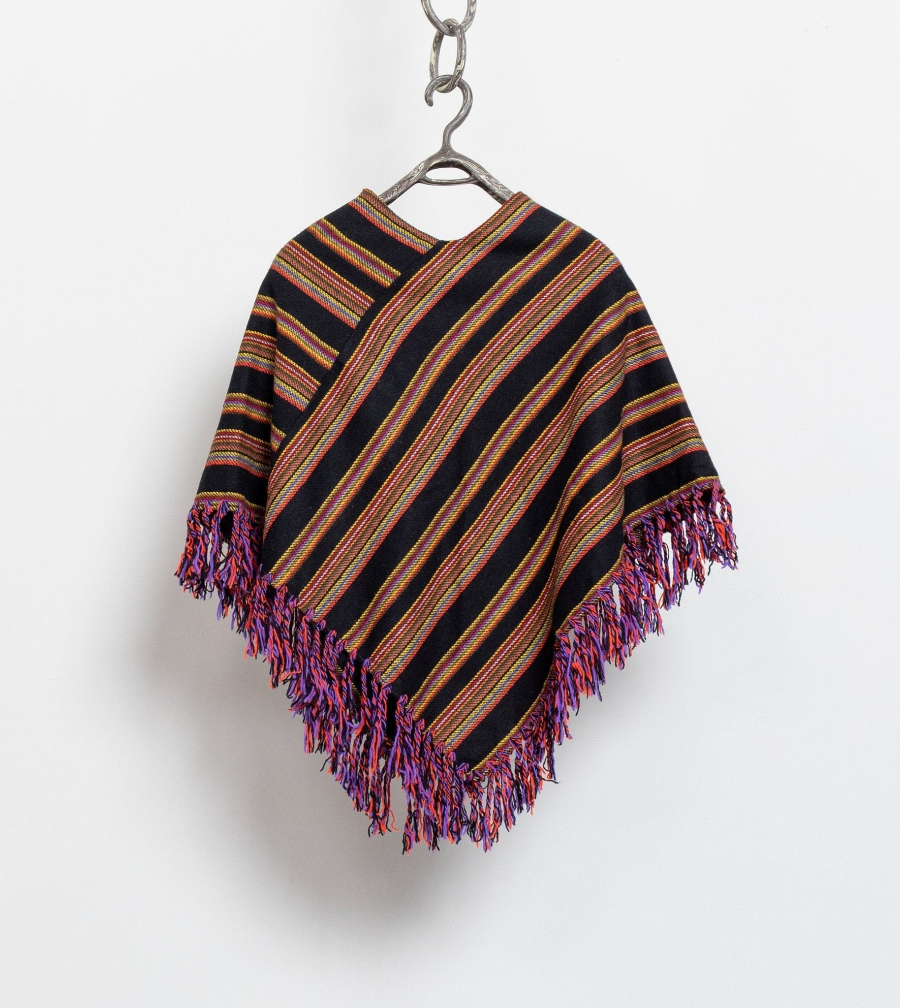 Striped poncho with fringes on a hanger against a white background