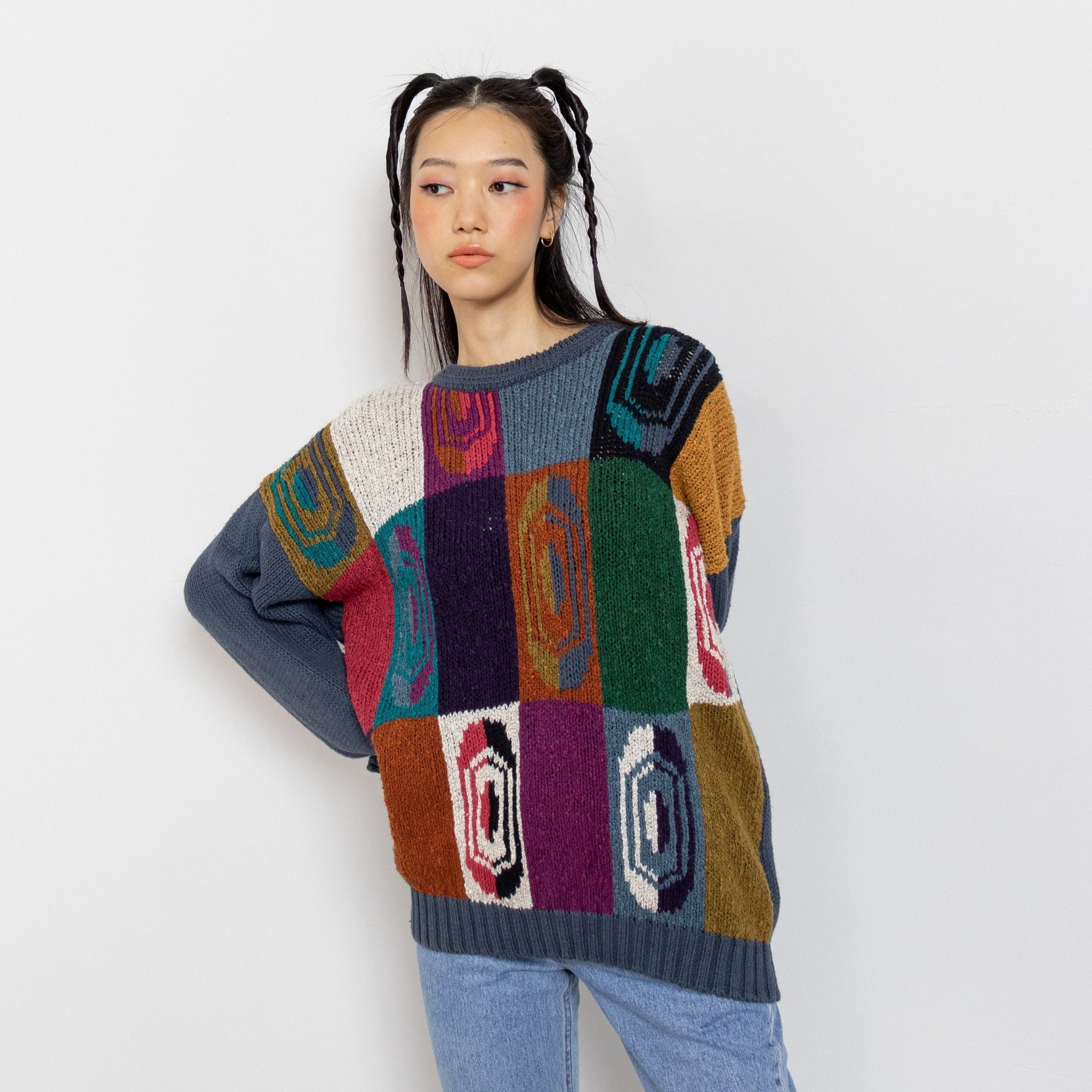 A person wearing a multicolored checkered cotton pullover with a geometric design.