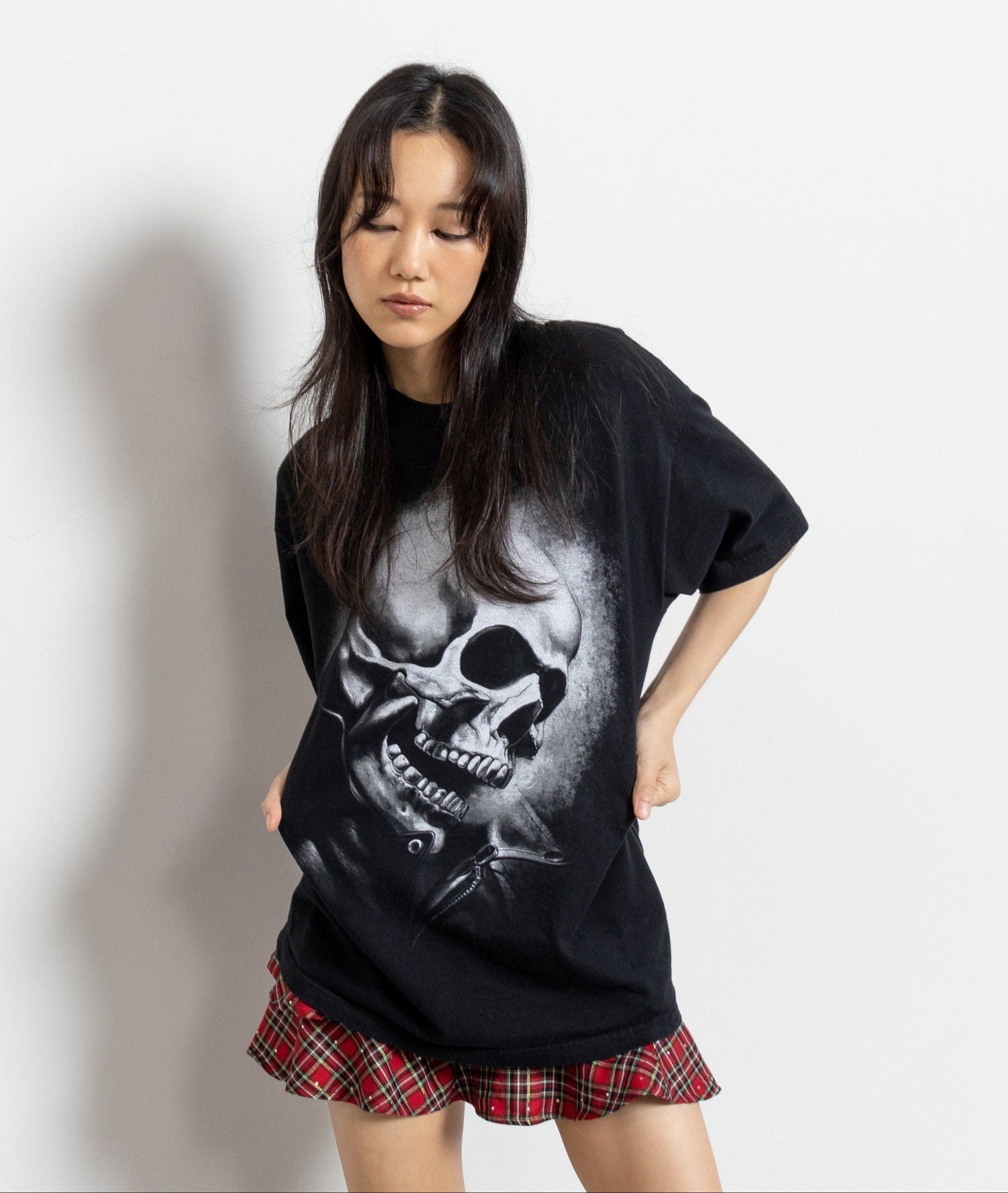 A person wearing a vintage black cotton t-shirt with a large skull graphic in the center.