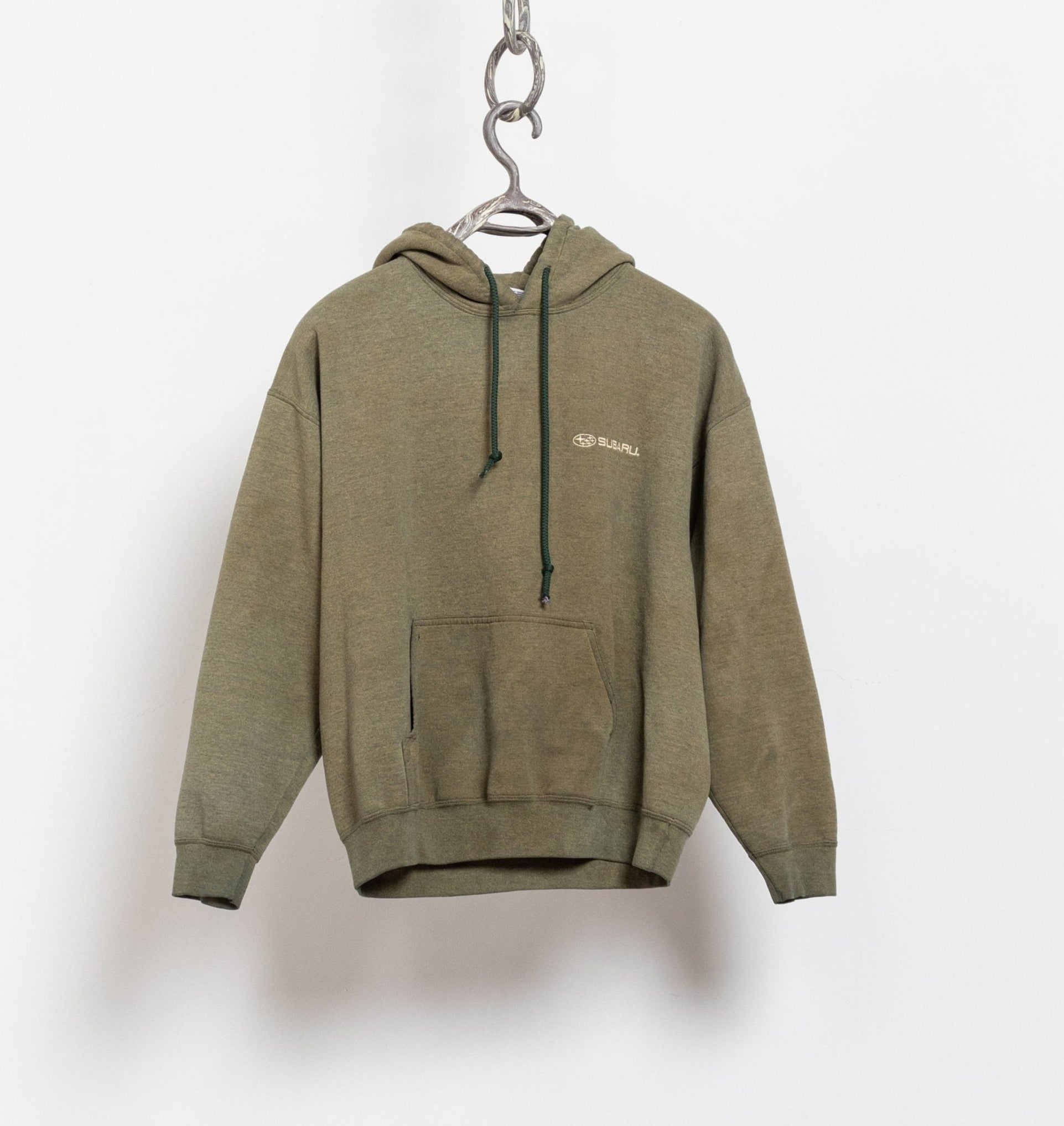 A greenish, distressed, pullover Subaru hooded sweatshirt hanging against a white background.