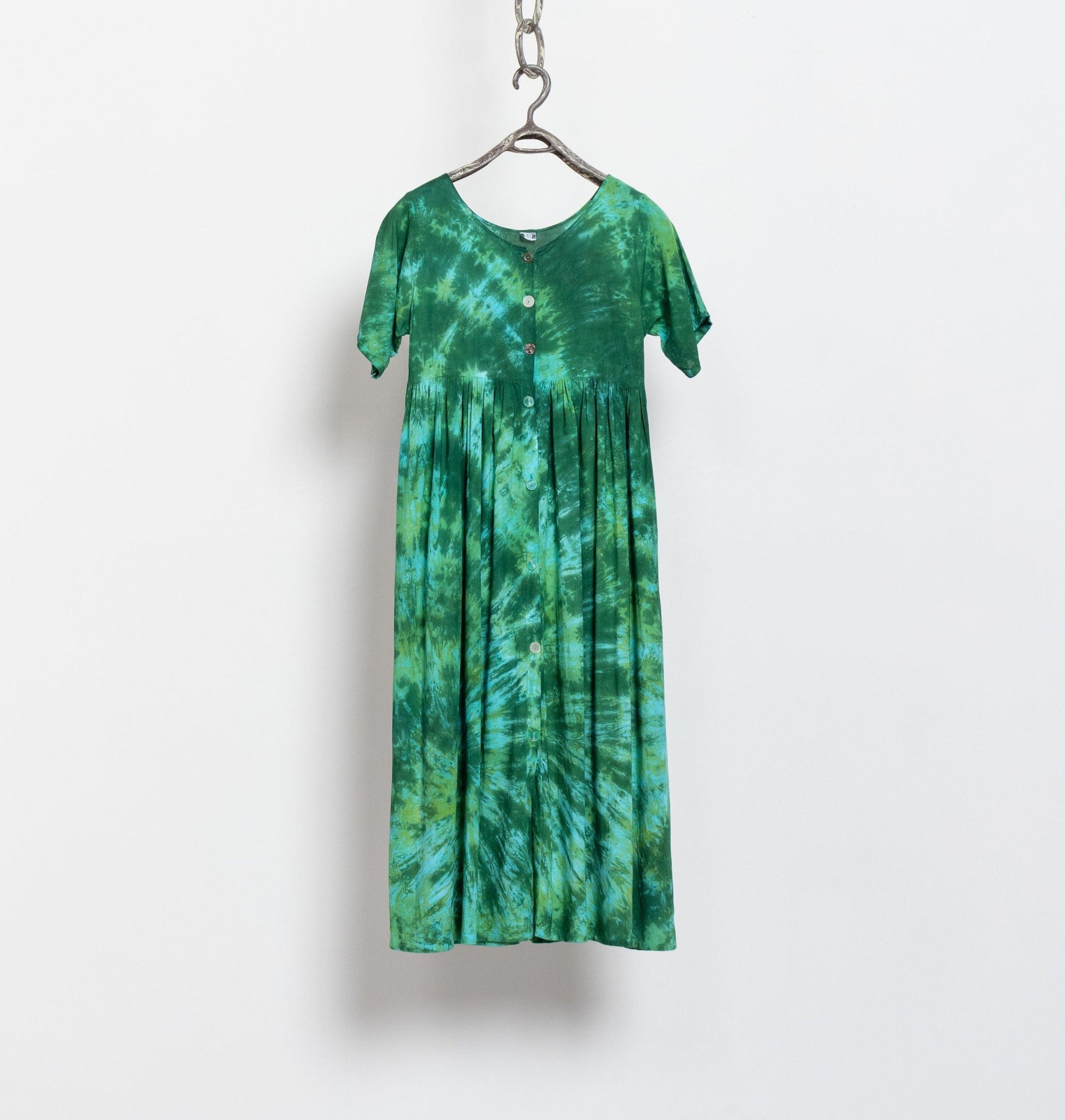 A vintage 90's green tie-dye short-sleeve maxi dress hanging against a white background, showcasing a tie-dye pattern with matching buttons and side ties.