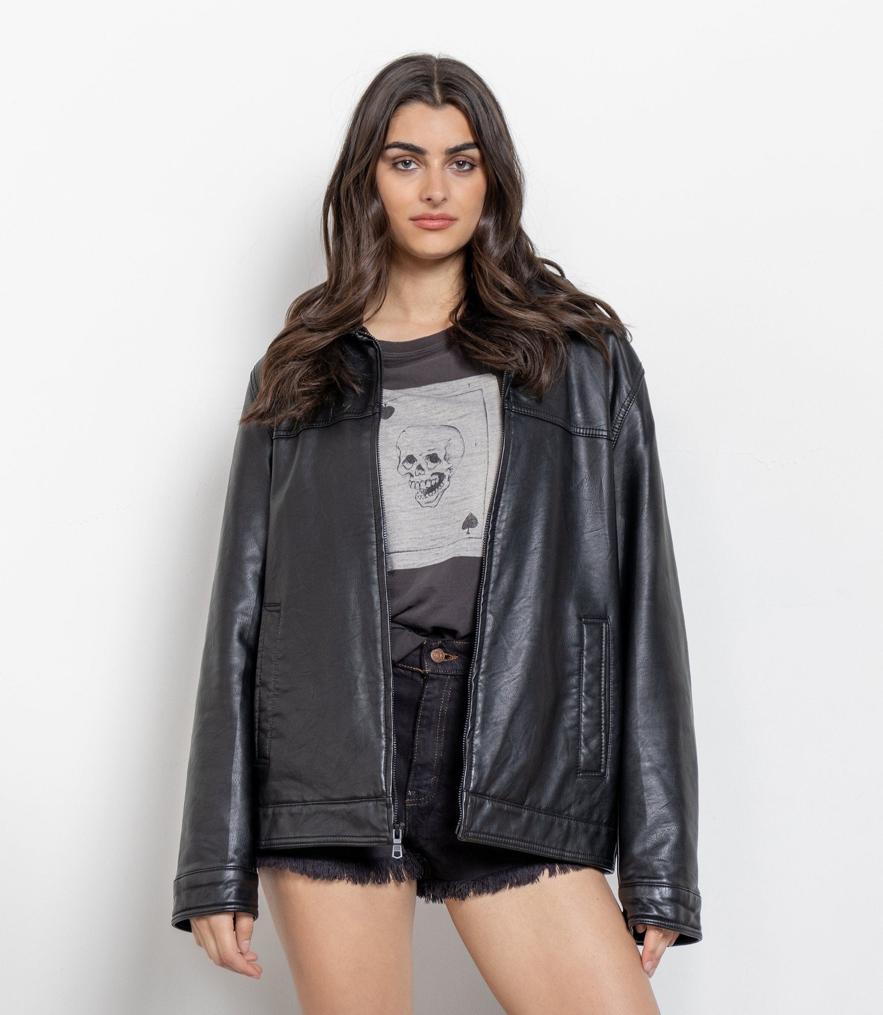Woman wearing a black leather jacket over a graphic t-shirt on a white background