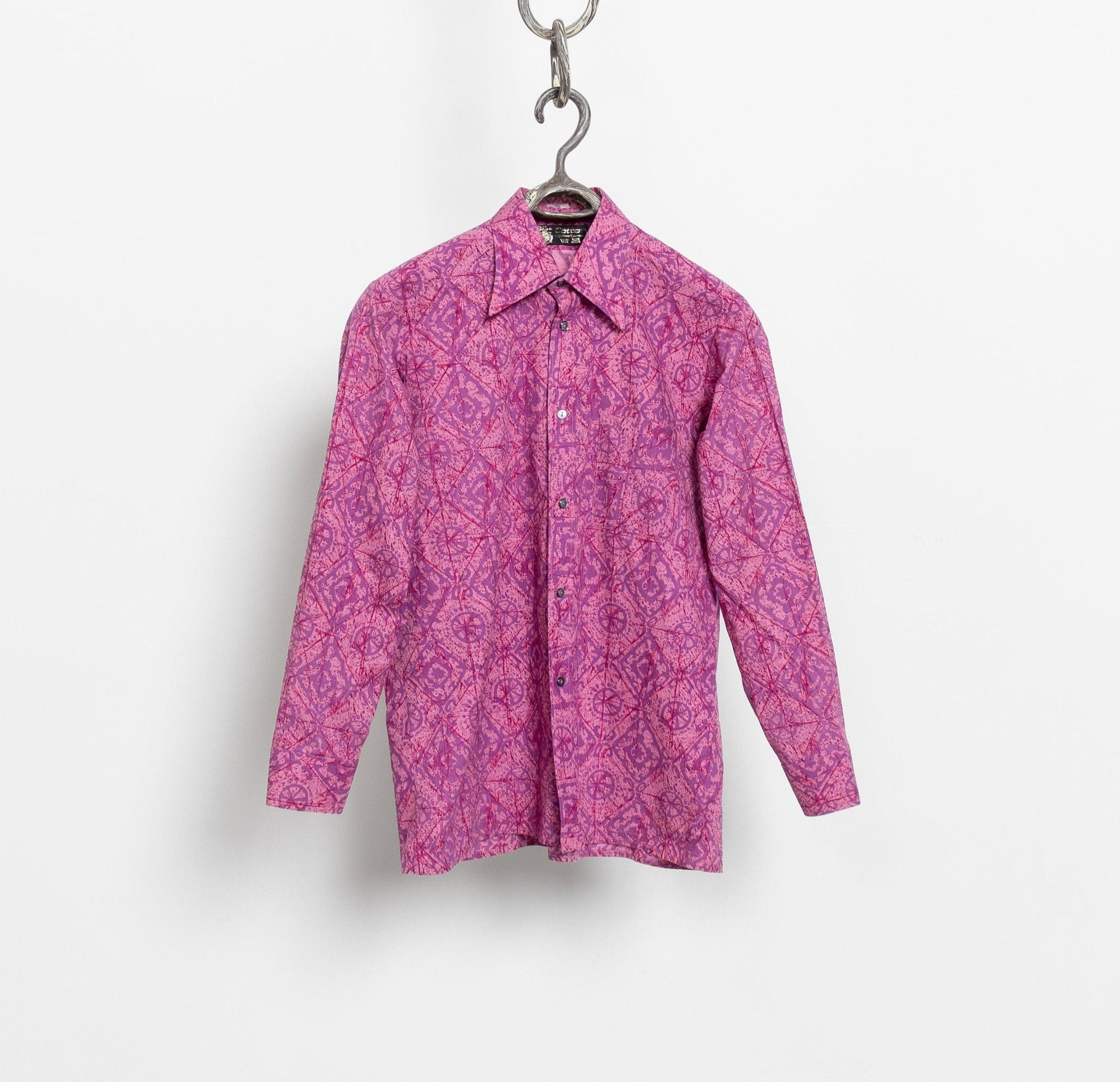 Pink patterned shirt on a hanger against a white background