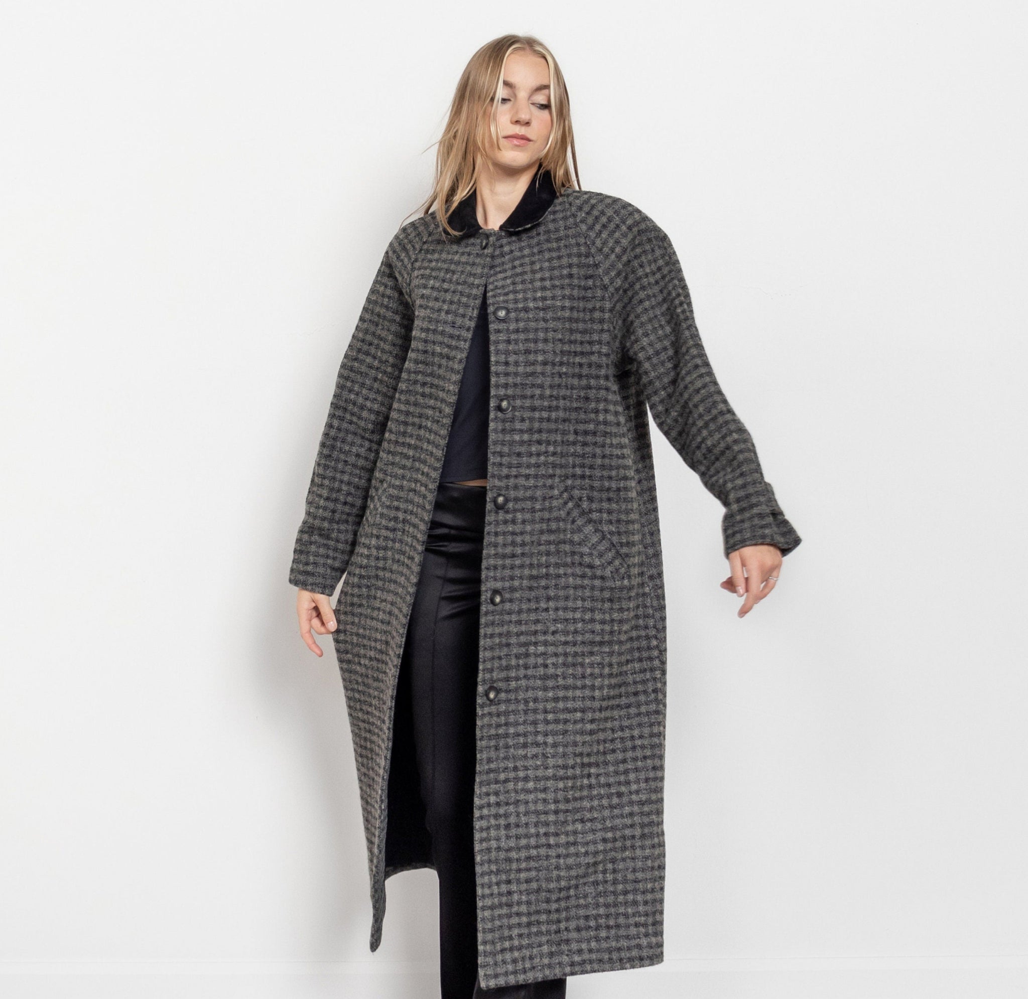 Person wearing a long gray checkered coat on a white background