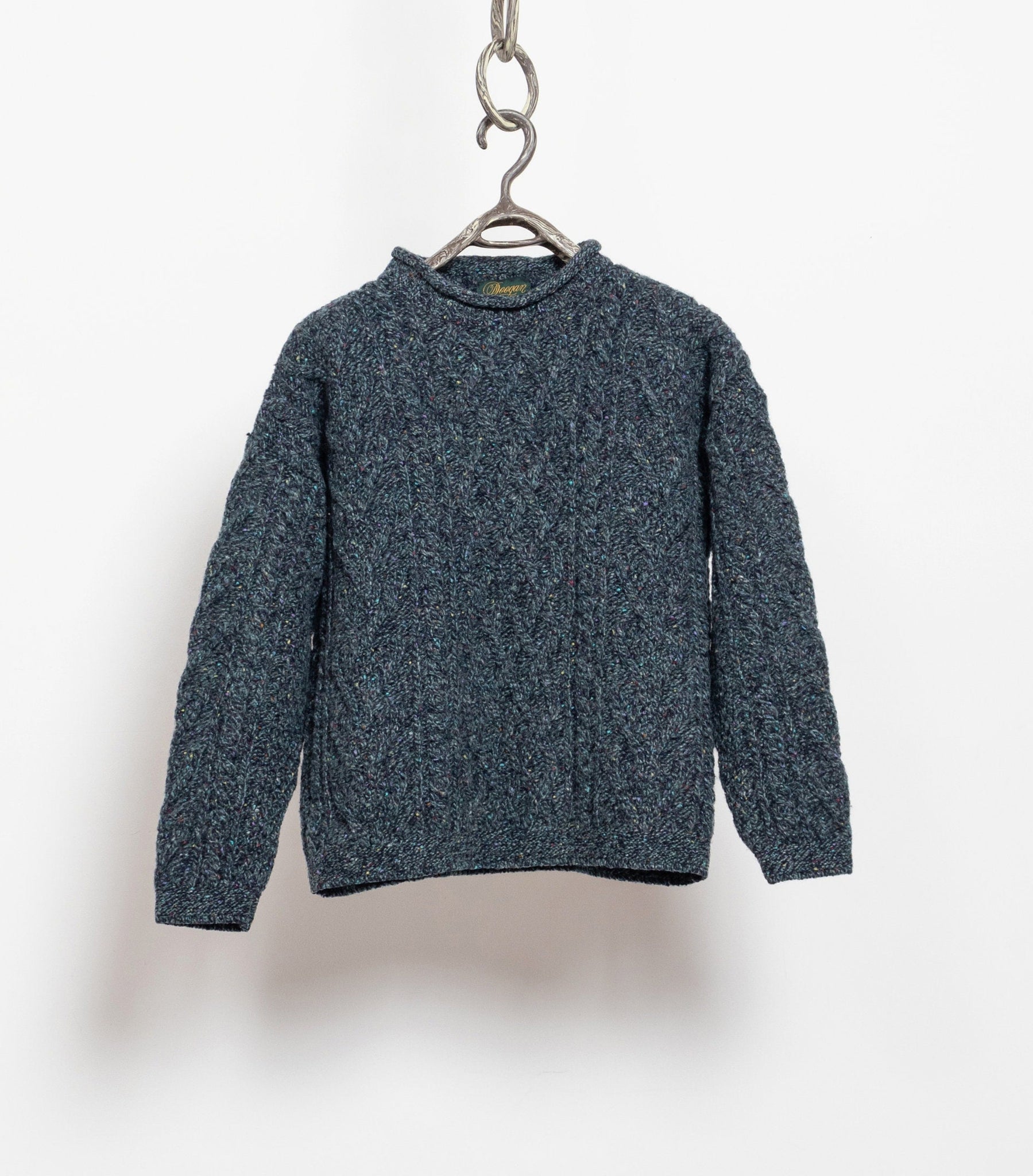 A vintage 90's blue-green flecked cable knit wool pullover sweater hanging against a white background.