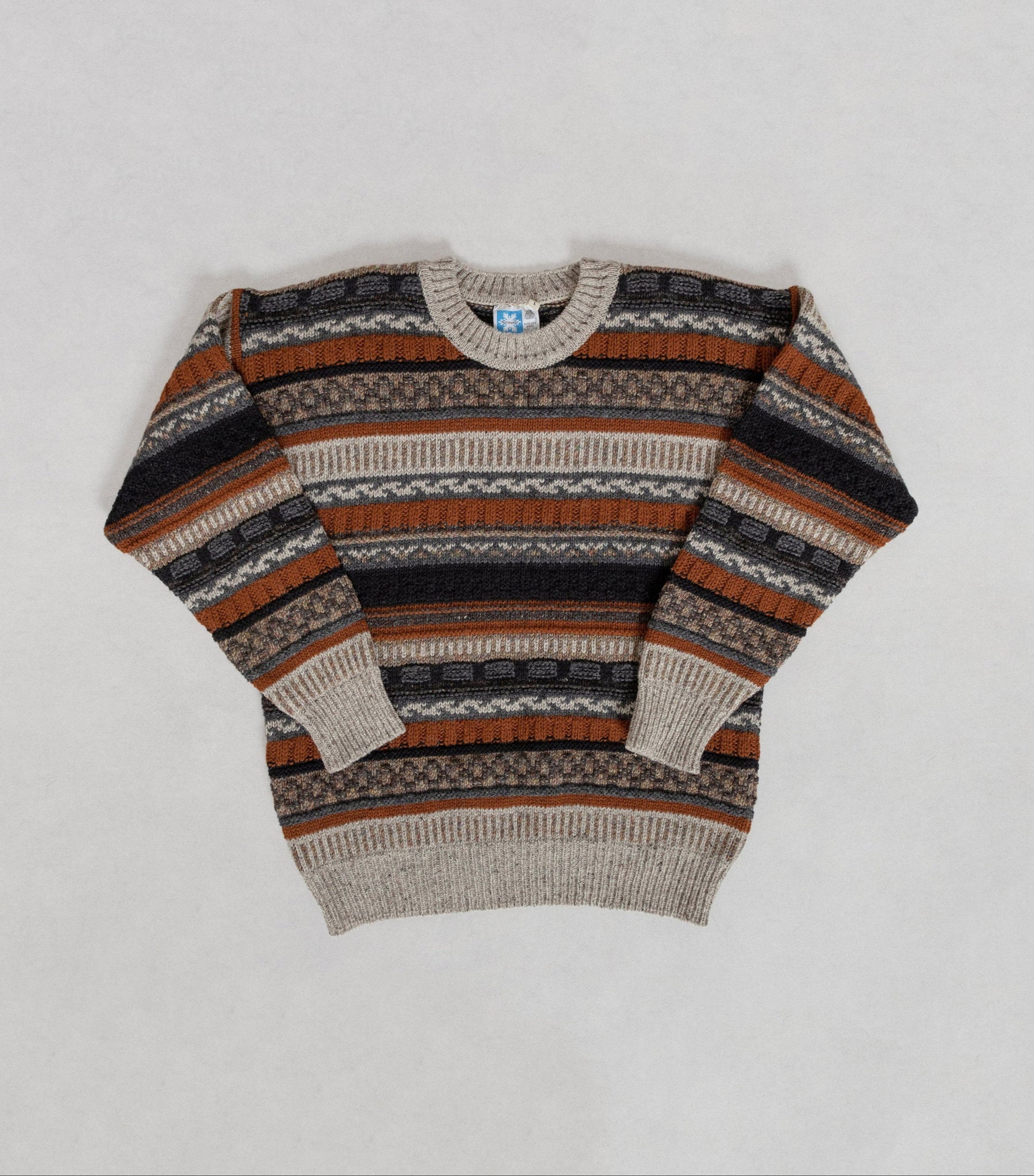 Striped sweater with brown, black, and beige pattern on a light gray background