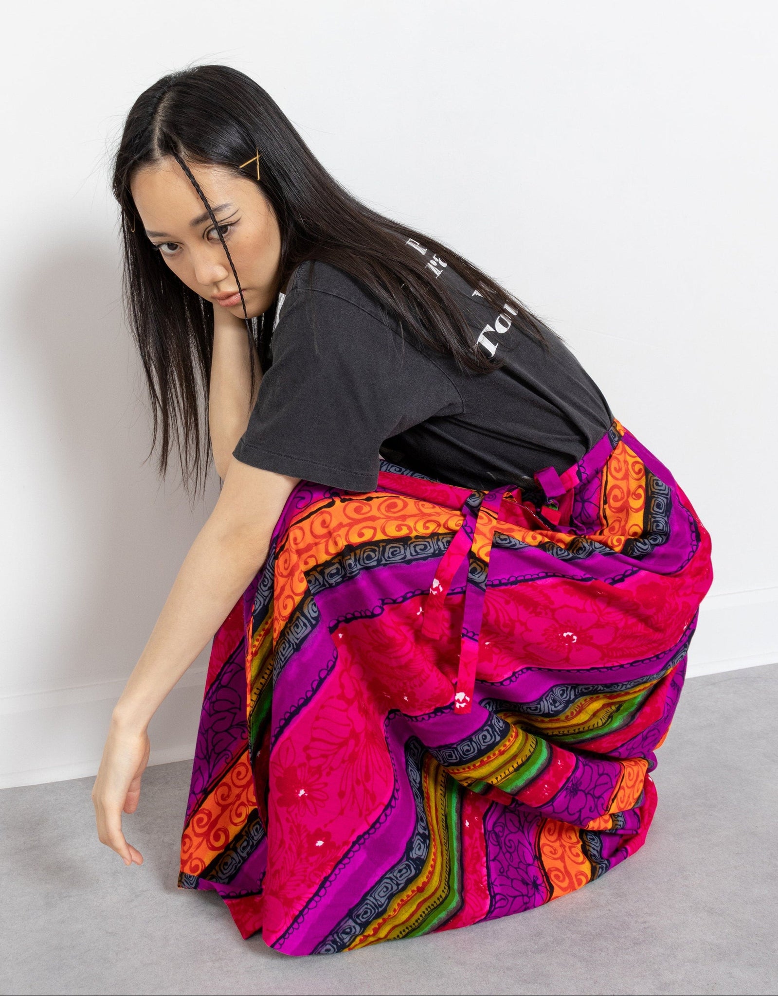 Woman wearing a colorful, patterned skirt with a plain background