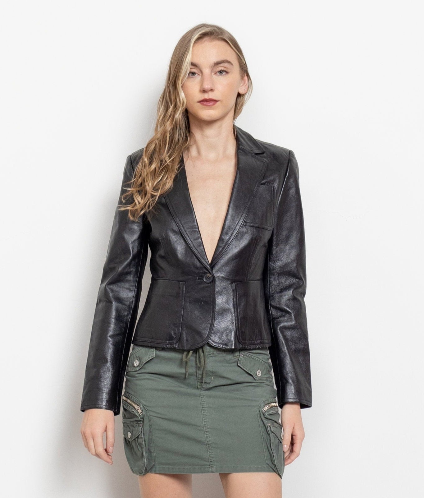 Woman wearing a black leather jacket and green skirt on a white background