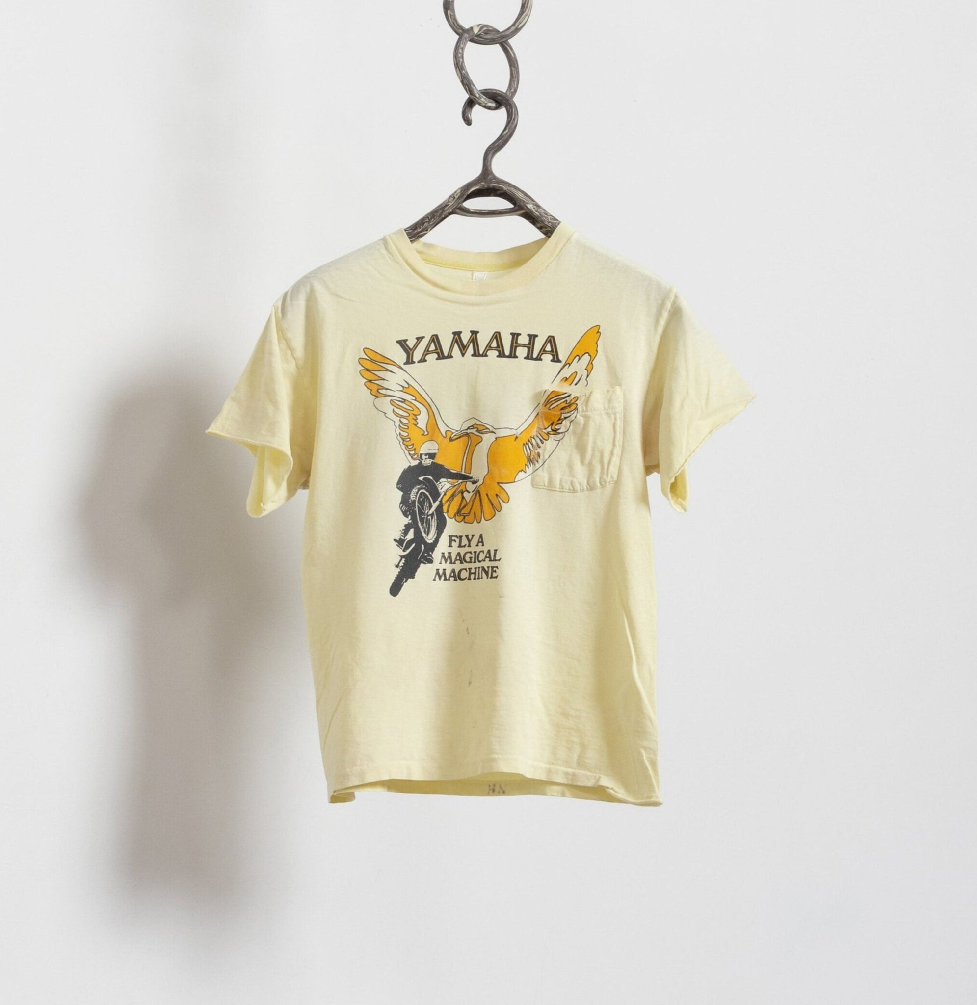 A yellow vintage Yamaha motorcycle graphic t-shirt hanging on a hanger against a white background.