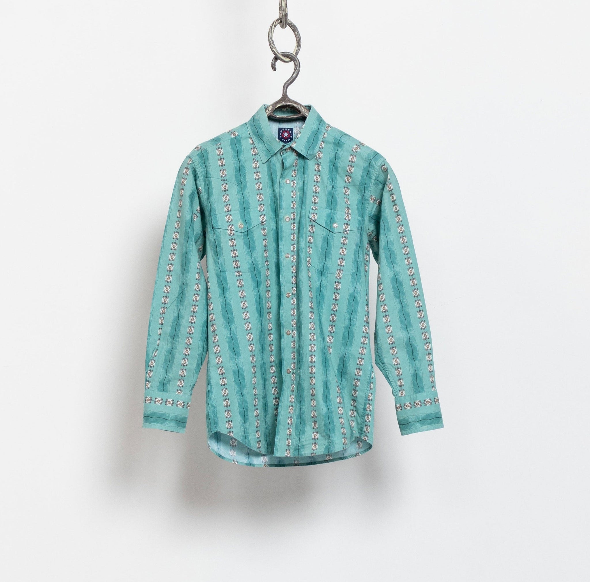 Vintage bright teal western cowlgirl blouse with a long-sleeve design, displayed on a hanger against a white background.