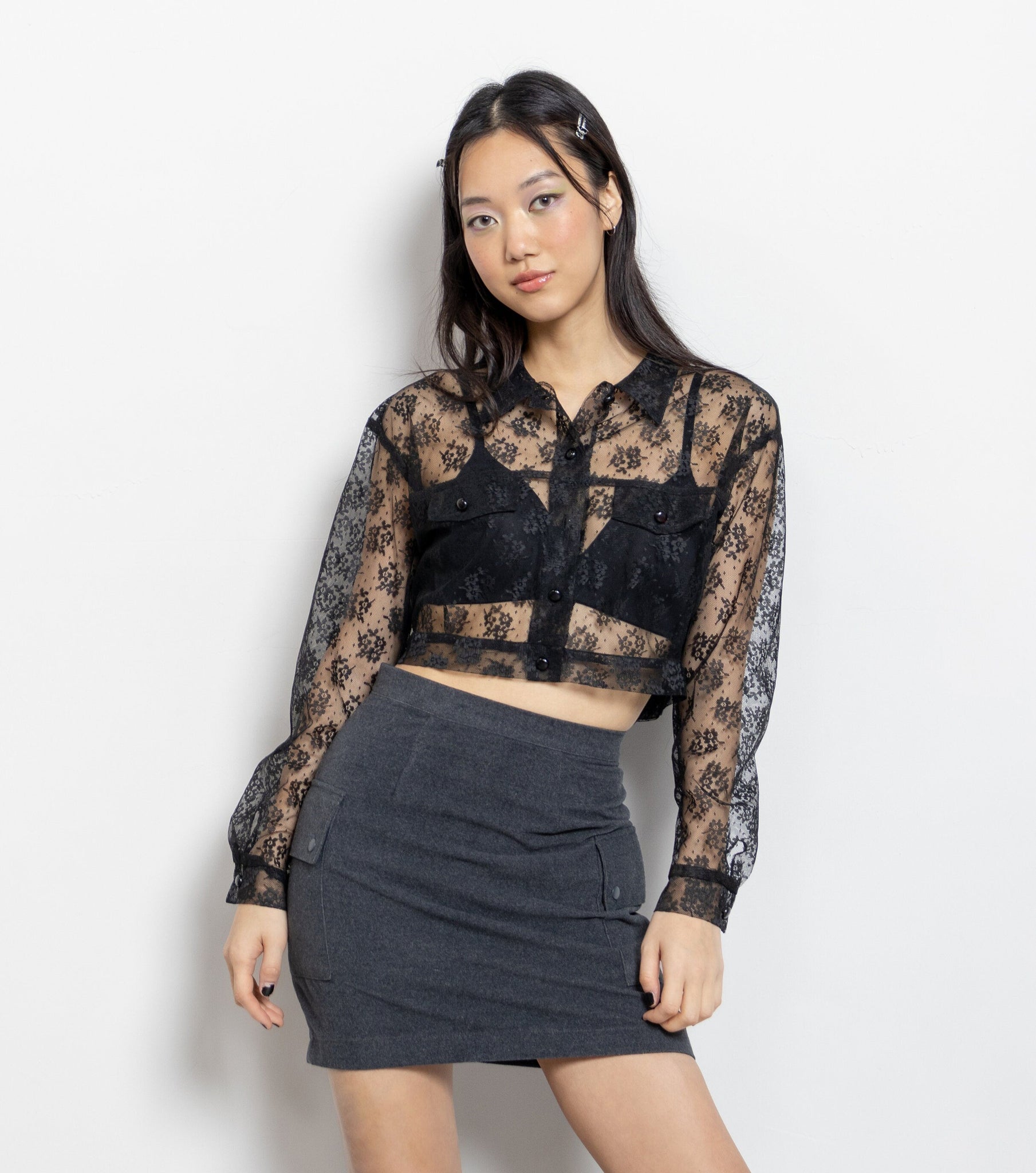 Woman wearing a black lace top and gray skirt on a white background