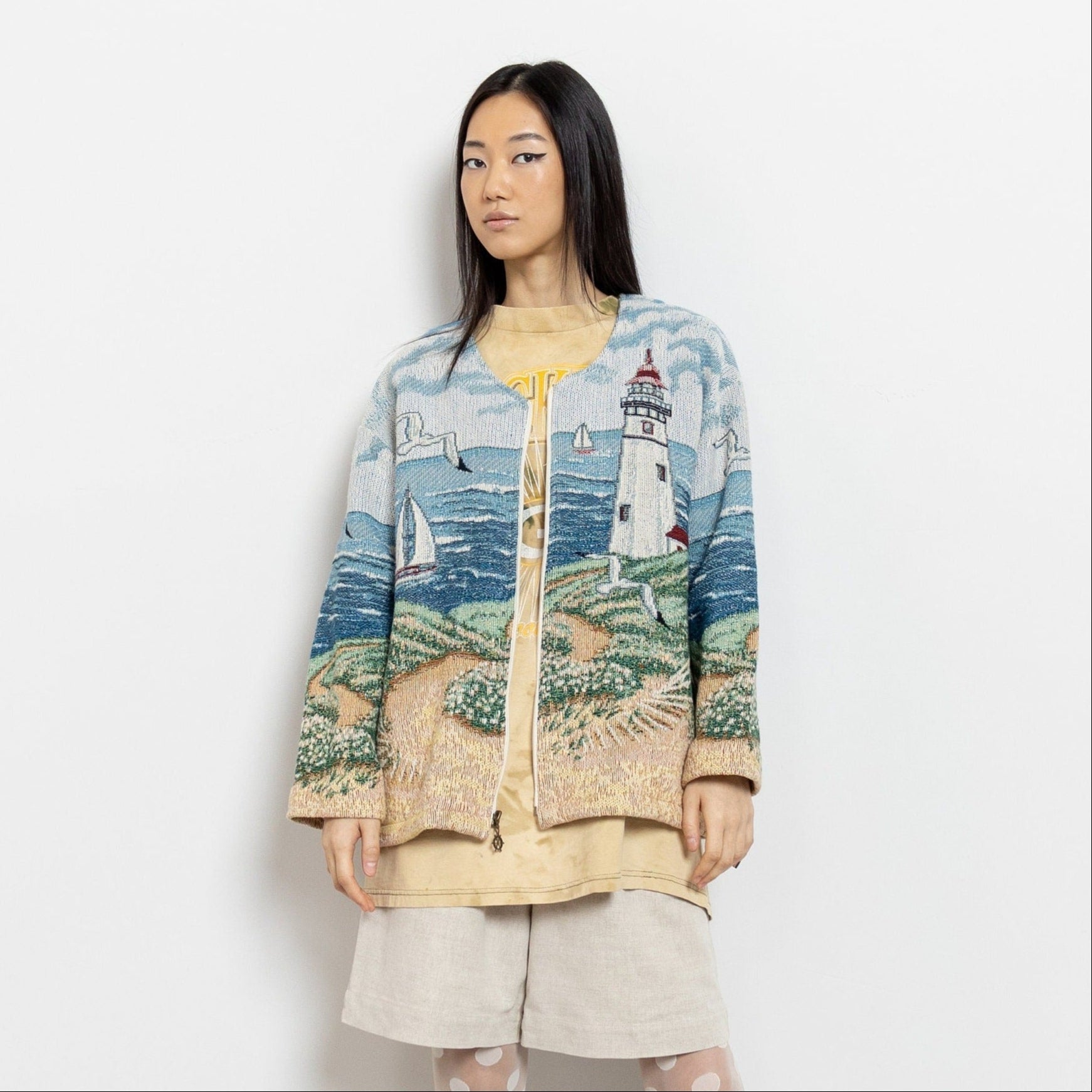 Woman wearing a cardigan with a scenic design on a plain background