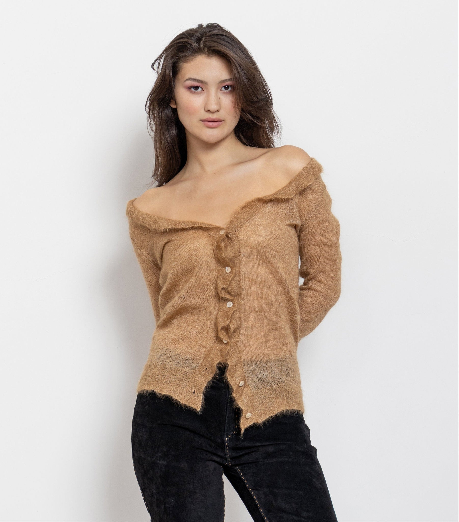 A female model wearing a vintage 90's sheer beige knitwear with a loose open knit pattern and a ruffled neckline.