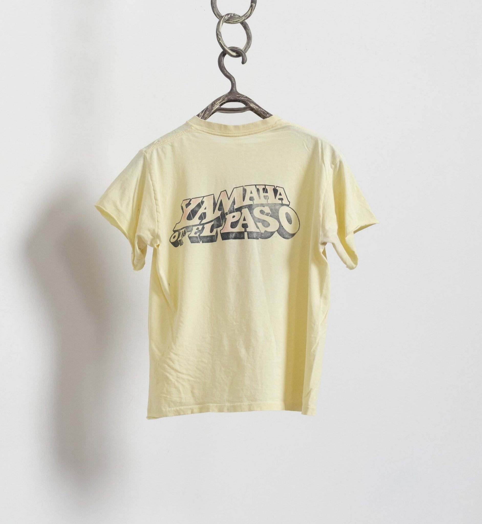 Yellow t-shirt with 'Yamaha' logo on a hanger against a white background